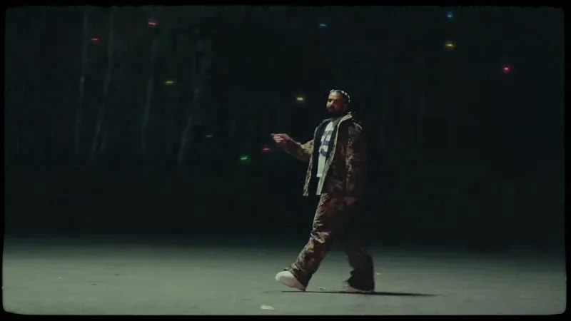 Still from Drake and Lil Yachty's Another Late Night music video: Drake standing in a dark lot at night with the tree line behind him
