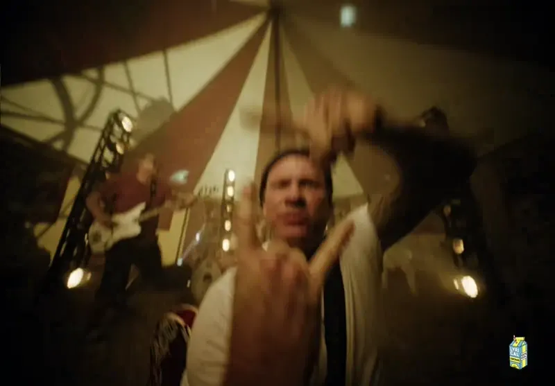 Still from blink-182's EDGING music video: the band performing under a carnival tent
